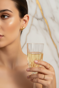 Gros plan boucles X dorées portées, fond marbre